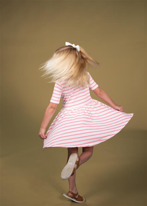 Kindergartner spinning in a pink and white dress. Happy.