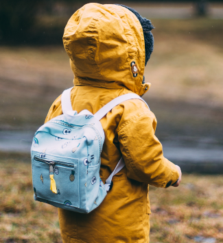 child with raincoat and small backpack on